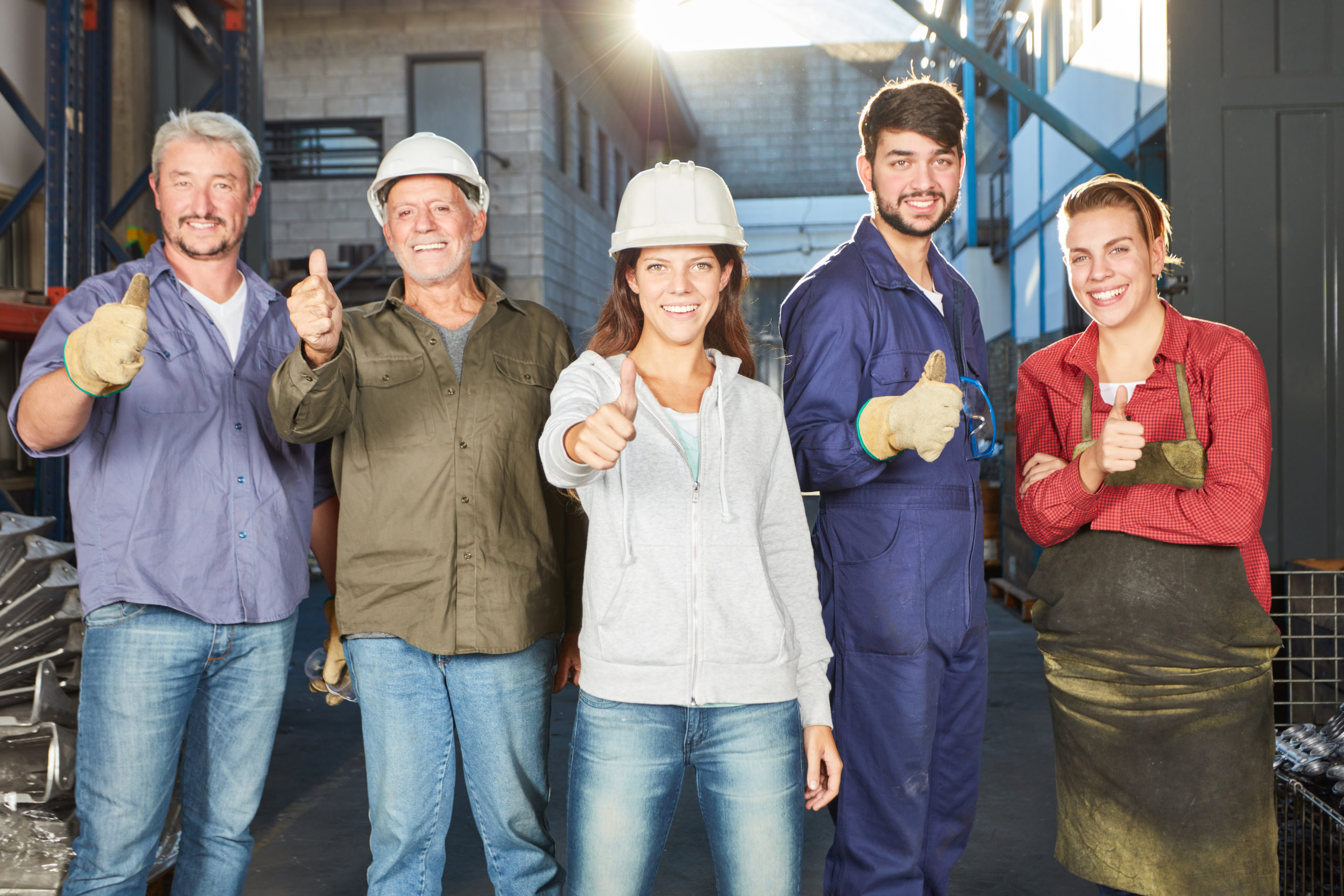 Gruppe Industrie Arbeiter in einer Fabrik zeigt mit den Daumen nach oben